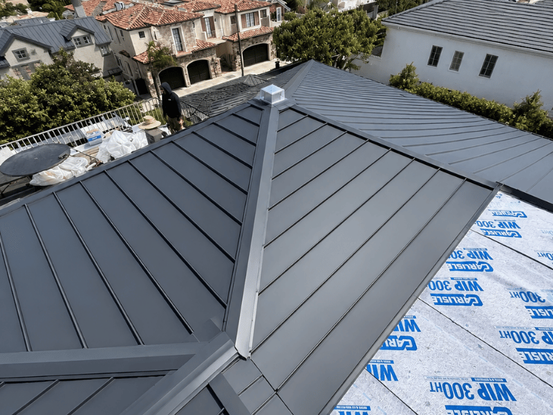 Standing seam metal roof installation in progress on a Southern California home, showing installed panels alongside Carlisle WIP 300HT high-temp underlayment.