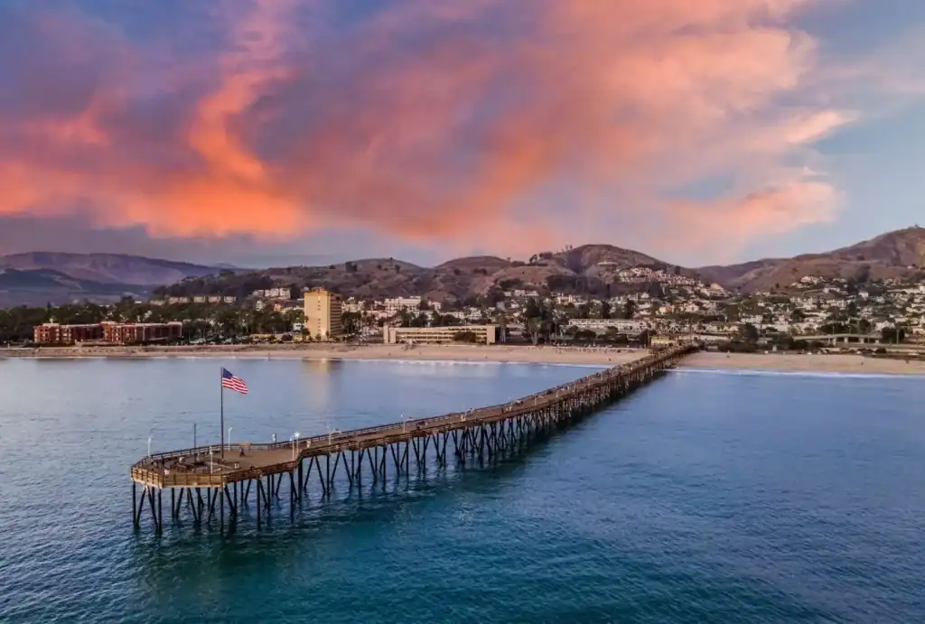 Ventura Pier at sunset with U.S. flag, beachfront, and Conejo foothills — Method Roofing Group serves Ventura County commercial and residential roofing.
