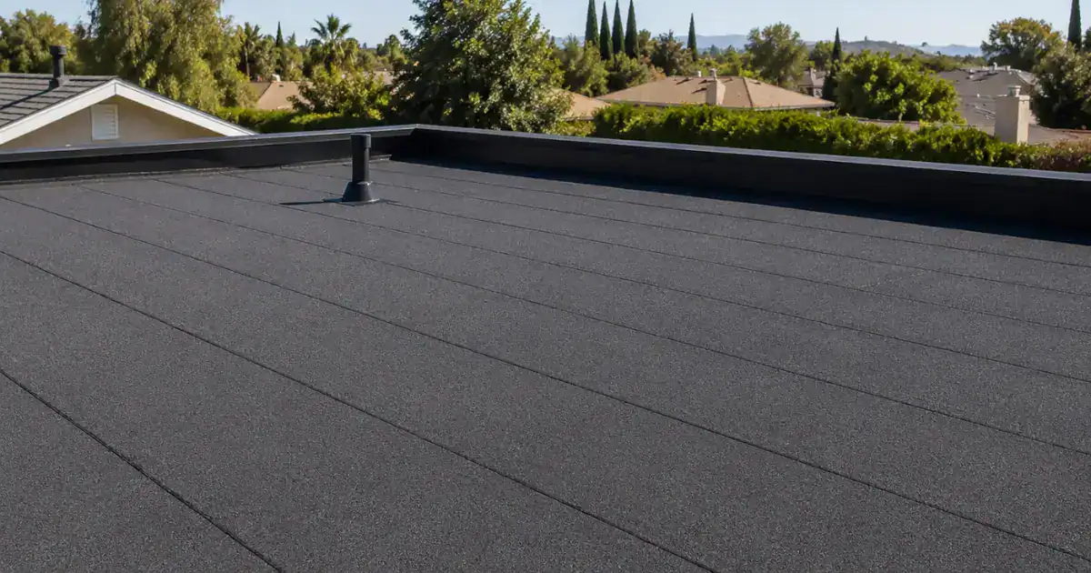 Finished gray granulated modified bitumen flat roof on a Southern California residential home with parapet edge and vent boot.