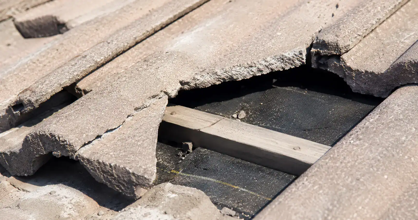 racked and broken concrete roof tiles on a Southern California home exposing the aged underlayment beneath — the most common cause of tile roof leaks.