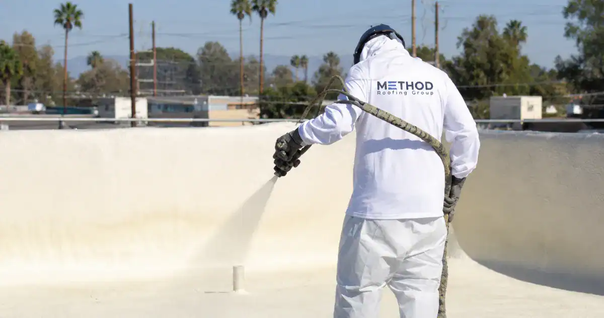 Method Roofing Group technician spray-applying a fluid-applied roof coating on a Southern California commercial flat roof — restoration done with proper prep.