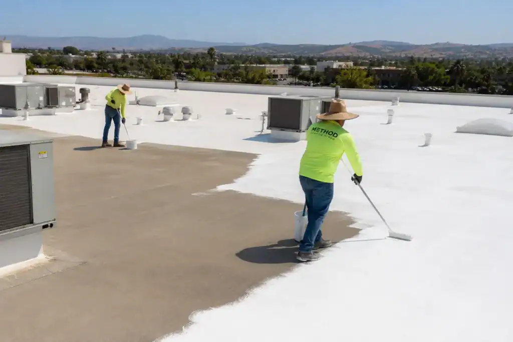 Roof restoration vs replacement — Method Roofing Group crew roller-applying a fluid-applied restoration system across a qualifying Southern California commercial roof.